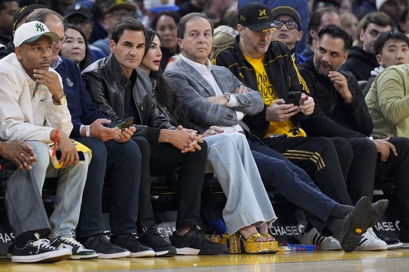 Former tennis player Roger Federer, third from left, sits courtside during the first half of an NBA basketball game between the Golden State Warriors and the San Antonio Spurs, Saturday, March 9, 2024 ...