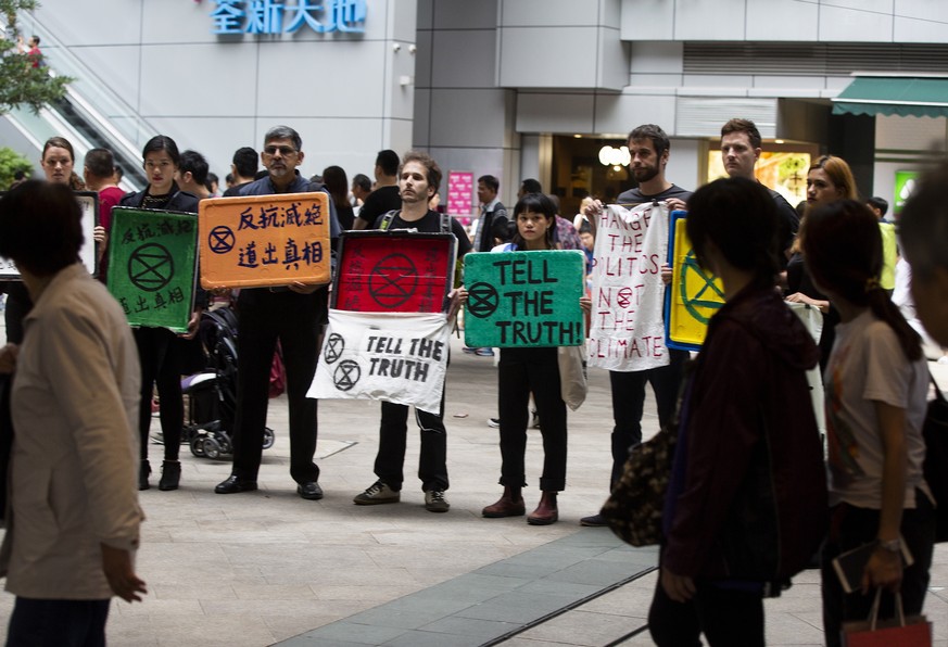 epa07546296 Members of Extinction Rebellion Hong Kong hold up banners demanding quick action on climate change in front of a giant planet earth globe at a shopping mall in Tsuen Wan, Kowloon, Hong Kon ...