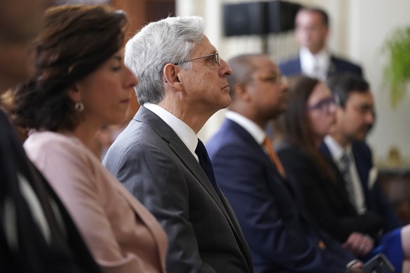 Secretary of Commerce Secretary Gina Raimondo, second from left, and Attorney General Merrick Garland center, listen as President Joe Biden speaks before signing an executive order aimed at promoting  ...