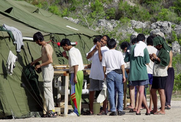 FILE - In this Sept. 21, 2001, file photo, men shave, brush their teeth and prepare for the day at a refugee camp on the Island of Nauru. Human rights groups accused Australia on Wednesday, Aug. 3, 20 ...