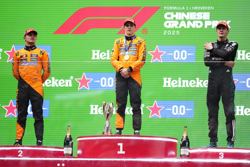McLaren driver Oscar Piastri of Australia, centre, is flanked on the podium with McLaren driver Lando Norris of Britain, left, and Mercedes driver George Russell of Britain after winning the Chinese F ...