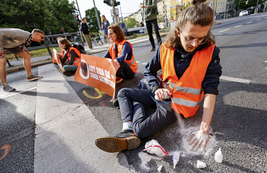 epa10645621 A Letzte Generation (Last Generation) climate activist glues his hand to the asphalt during a climate protest in Berlin, Germany, 22 May 2023. The activists gathered to demand climate coun ...