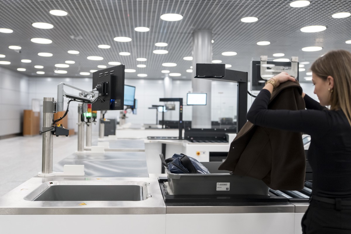 Ein Testprobandin demonstriert das Automated Tray Return System bei dem neu eingerichteten CT-Scanner fuer das Handgepaeck der Passagiere und des Personals im neuen Sicherheitskontrollgebaeudes (SKG)  ...