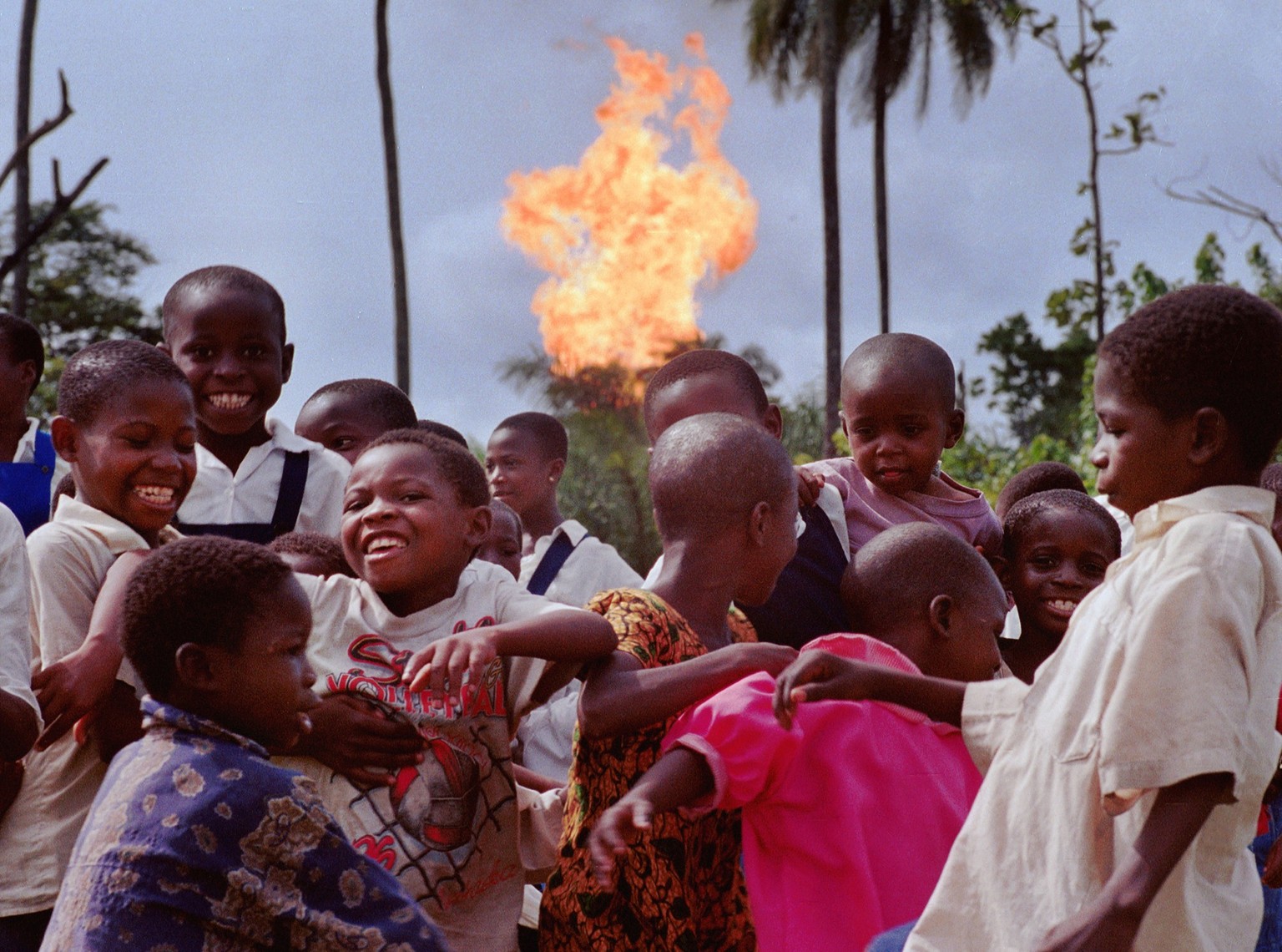 390464 20: Children in the Nigerian village of Akaraolu play at recess while the nearby Oshie gas flare roars on. No one in the village under the age of 30 can remember a time before what they simply  ...