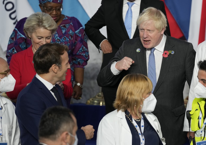 British Prime Minister Boris Johnson, center, pumps fists with French President Emmanuel Macron, left, during a group photo with medical personnel at the La Nuvola conference center for the G20 summit ...