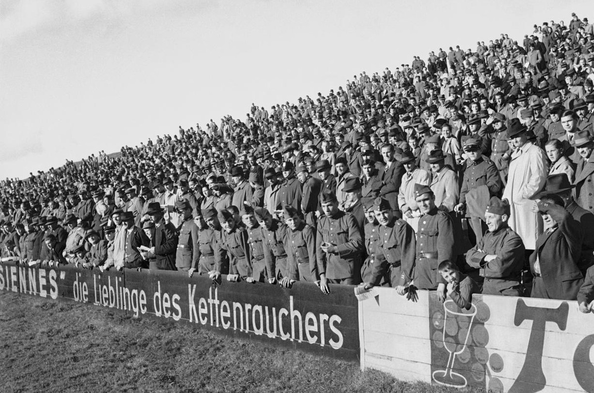 Zuschauer, darunter etliche Soldaten, verfolgen am 5. November 1939 im Wankdorf-Stadion in Bern hinter der Zigaretten-Bandenwerbung "Parisiennes, die Lieblinge des Kettenrauchers" ein Traini ...