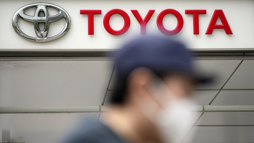 A man walks past a Toyota dealer in Tokyo on May 11, 2022. Toyota Motor Corp. reported Thursday, Aug. 4, 2022 a quarterly profit of 736.8 billion yen ($5.5 billion), down from 897.8 billion yen the pr ...