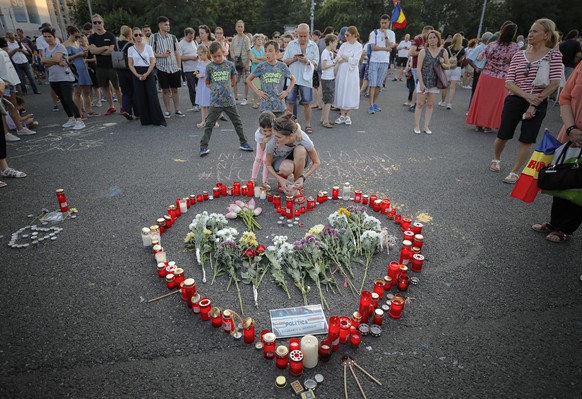 People light candles outside the government headquarters in memory of a 15 year-old girl, raped an killed in southern Romania, after police took 19 hours from the moment she called the country&#039;s  ...