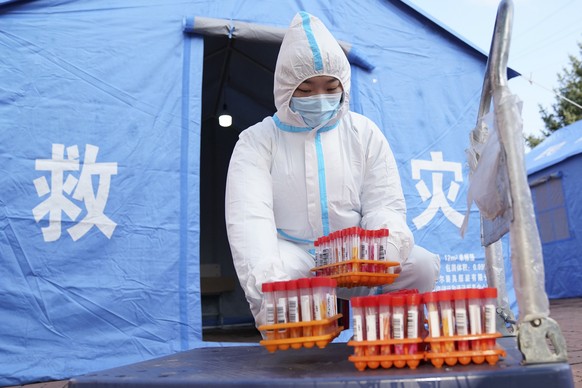 In this photo released by China&#039;s Xinhua News Agency, a worker in protective clothing handles COVID-19 test samples in Bayan County of Harbin city in northeastern China&#039;s Heilongjiang Provin ...