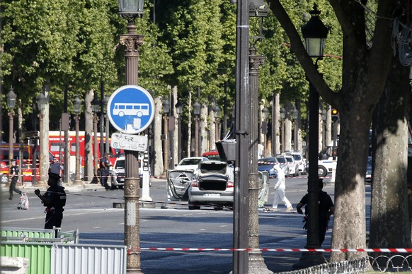 Scientific police officers investigate on the suspected car, right, after a man rammed into a police convoy on the Champs Elysees avenue in Paris, Monday, June 19, 2017. France&#039;s interior ministe ...
