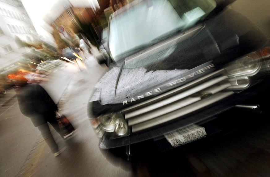 Eine Passantin geht am Dienstag, 21. Oktober 2003, in Zuerich an einem Gelaendewagen vorbei. Laut der Umweltorganisation Greenpeace hat die Schweiz im europaeischen Vergleich eine besonders klimaschae ...