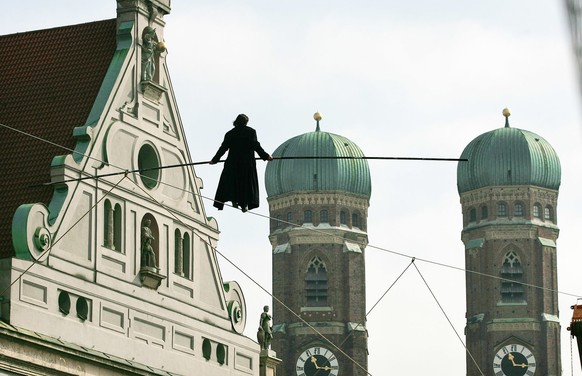 Hoch ueber der Fussgaengerzone geht der Schweizer Artist Freddy Nock am Donnerstag, 31. Maerz 2005, vor den Tuermen der Frauenkirche in Muenchen mit wehendem Mantel ueber ein Hochseil. In 30 Meter Hoe ...