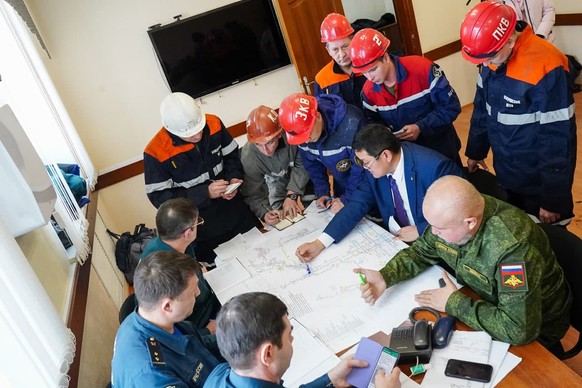 In this photo provided by the Governor of Kemerovo Region Press Office, rescuers and officials attend a meeting, after the accident at the Listvyazhnaya coal mine about 100 km (62 mies) of the Siberia ...