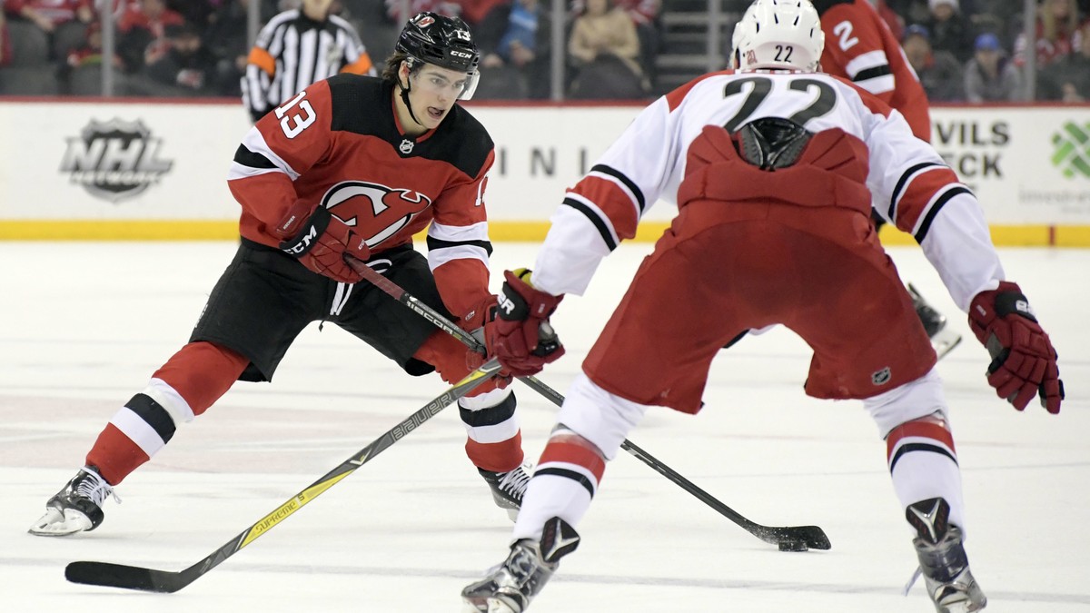 New Jersey Devils center Nico Hischier (13) looks to pass the puck as Carolina Hurricanes defenseman Brett Pesce (22) defends during the second period of an NHL hockey game Thursday, Feb. 15, 2018, in ...