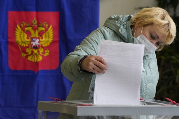 A woman casts her ballot during the State Duma, the Lower House of the Russian Parliament and local parliaments elections at a polling station in St. Petersburg, Russia, Saturday, Sept. 18, 2021. Sund ...