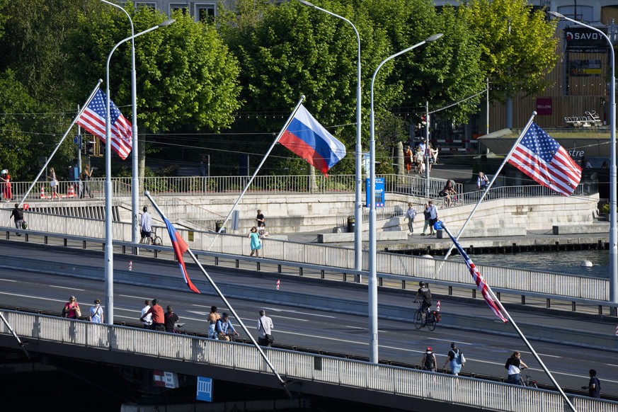 People cross a bridge decorated with United States and Russian flags in Geneva, Switzerland, Tuesday, June 15, 2021. US President Joe Biden is scheduled to meet with Russian President Vladimir Putin i ...