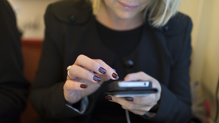 Eine Frau twittert im SBB-Zug von Zuerich nach Bern ueber ihr Handy, aufgenommen am 7. Februar 2013.(KEYSTONE/Gaetan Bally)