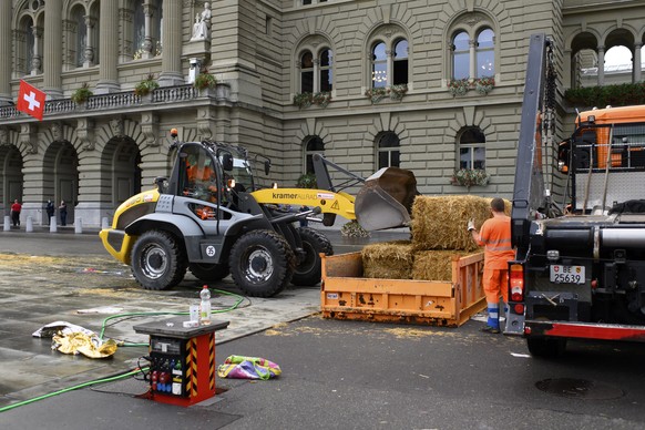 epa08689760 Cleaning forces of the city of Berne remove bales of straw after police cleared the Bundesplatz of climate activists during the Rise up for Change week of action in front of the Bundeshaus ...