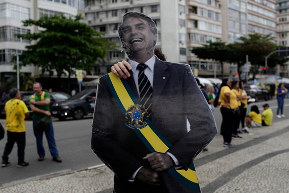 A supporter of opposition presidential candidate Flavio Bolsonaro carries an image of Flavio Bolsonaro's father, former President Jair Bolsonaro, as he arrives for a campaign rally in Rio de Jane ...