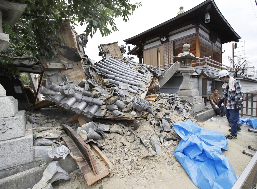 The gate of Myotoku-ji temple collapses after an earthquake hit Ibaraki City, Osaka, western Japan, Monday, June 18, 2018. A strong earthquake knocked over walls and set off scattered fires around met ...