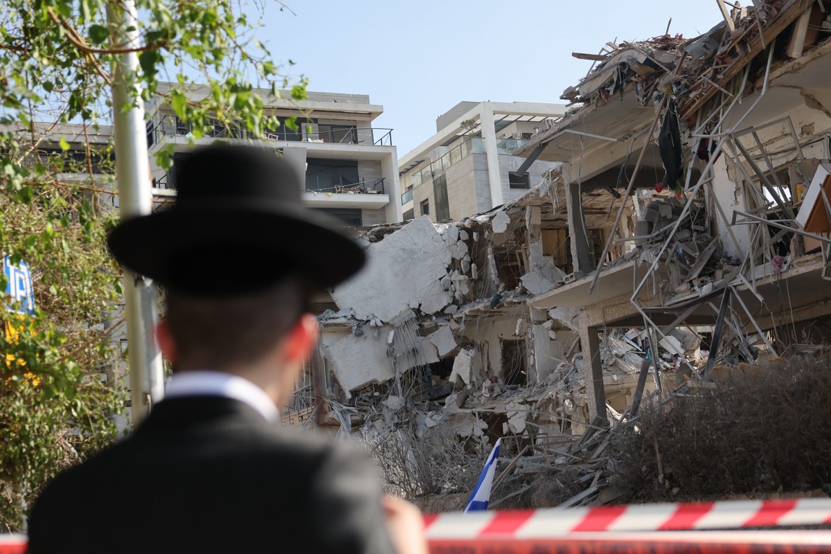 epaselect epa12174616 A person stands near a damaged residential building after a ballistic missile strike in Tel Aviv, Israel, 14 June 2025. Israel's military said Iran launched dozens of missil ...
