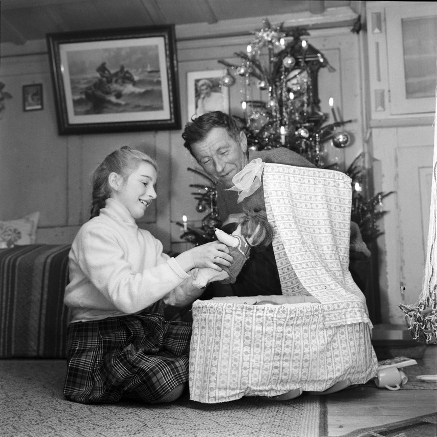 Weihnachten bei einem Fischer in Ermatingen. Die Tochter praesentiert dem Vater ihre Puppe und die Puppenwiege, die sie geschenkt bekommen hat. Aufgenommen am 24. Dezember 1958. (KEYSTONE/Photopress-A ...