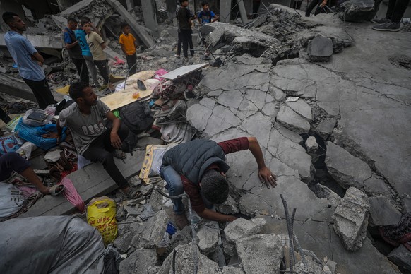 epa11304409 Palestinians search for bodies and survivors amidst the rubble of a destroyed house following an Israeli air strike in Al Nusairat refugee camp, southern Gaza Strip, 27 April 2024. More th ...
