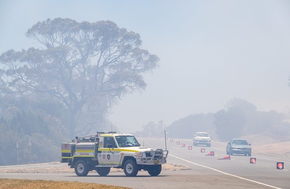 epa08918577 Emergency vehicles drive through bushfire smoke on Patterson Road in Kwinana, south of Perth, Australia, 04 January 2021. West Australian fire authorities had issued emergency warnings for ...