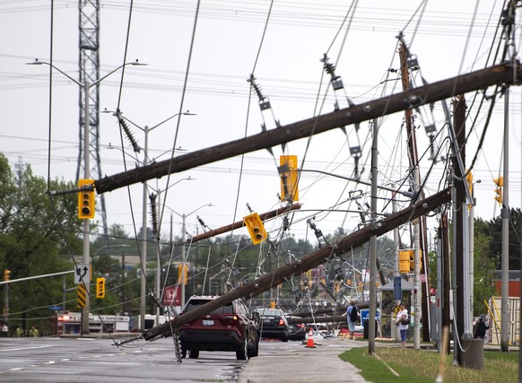 A vehicle is seen among downed power lines and utility poles after a major storm on Merivale Road in Ottawa, Canada, on Saturday, May 21, 2022. (Justin Tang/The Canadian Press via AP)