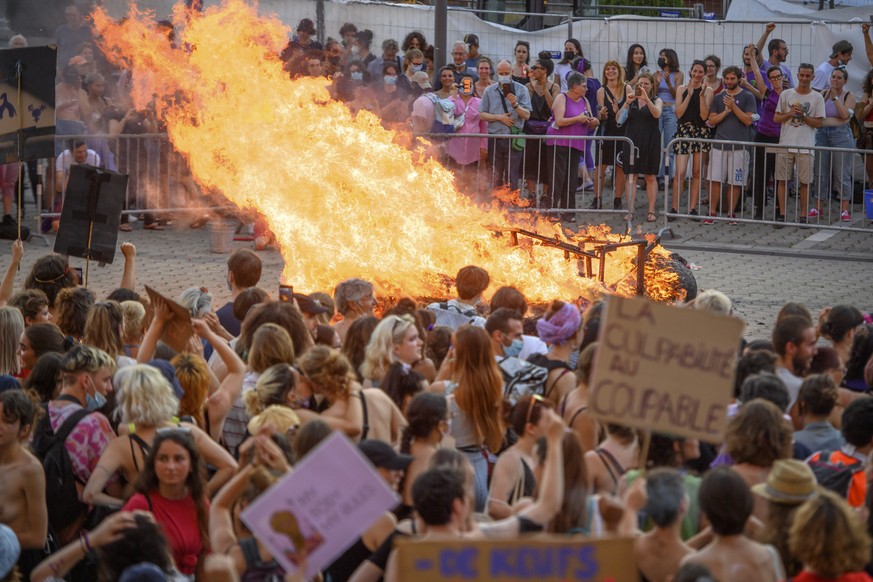 Des femmes manifestent en regardant un bonhomme de paille representant le patriarcat bruler lors d&#039;une manifestation de la greve des femmes / greve feministe, 30 ans apres la premiere greve des f ...