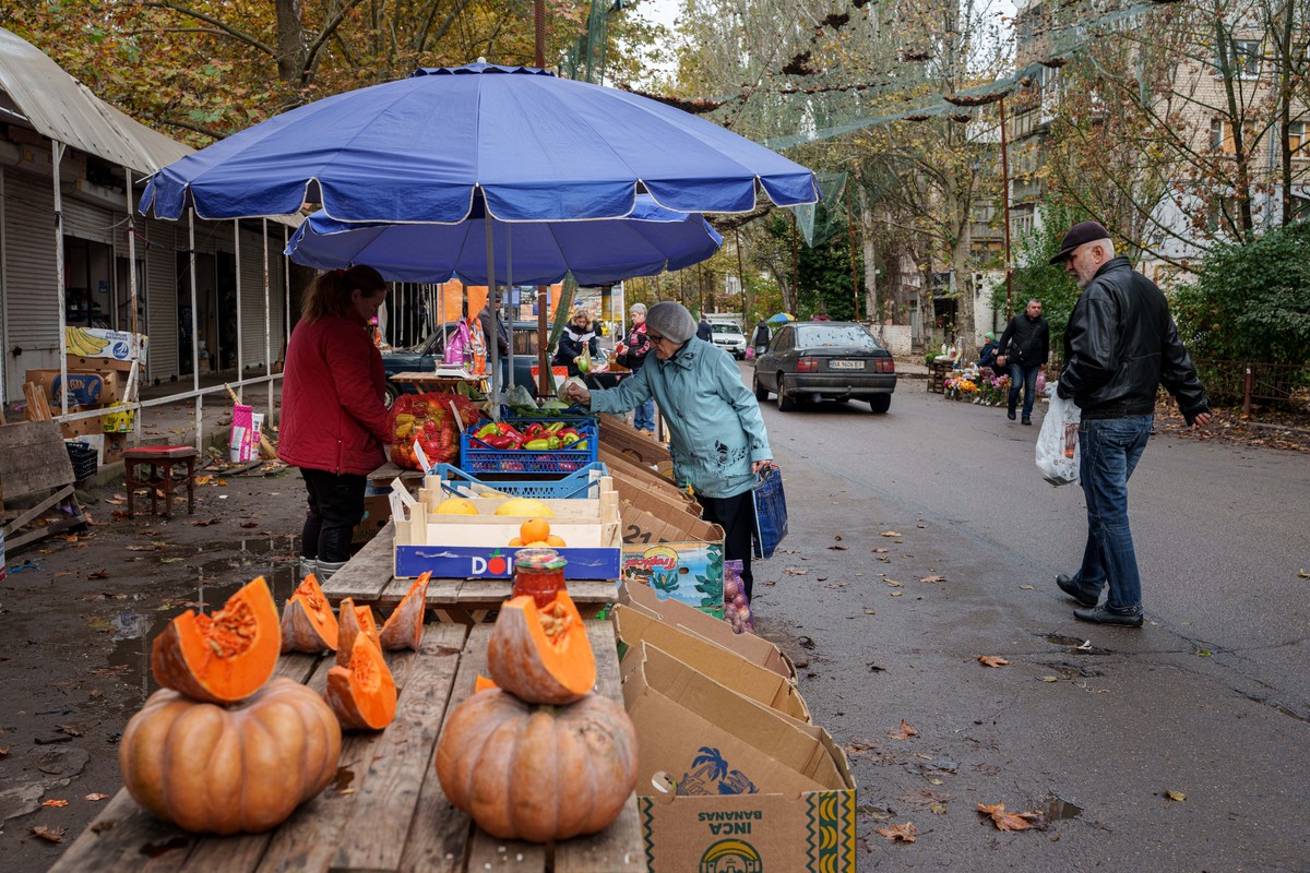 En elderly woman buys vegetables at a local market beneath anti-drone nets stretched over a street during a local ceasefire linked to a humanitarian aid mission in Oleshky, in Ukraine's Kherson r ...