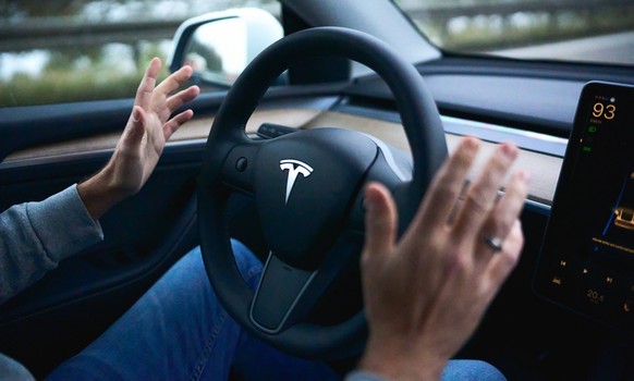 Bavaria, Germany - November 22, 2024: Symbolic image for autonomous driving with a Tesla. The driver of a Tesla electric car keeps his hands away from the steering wheel while the vehicle is driving a ...