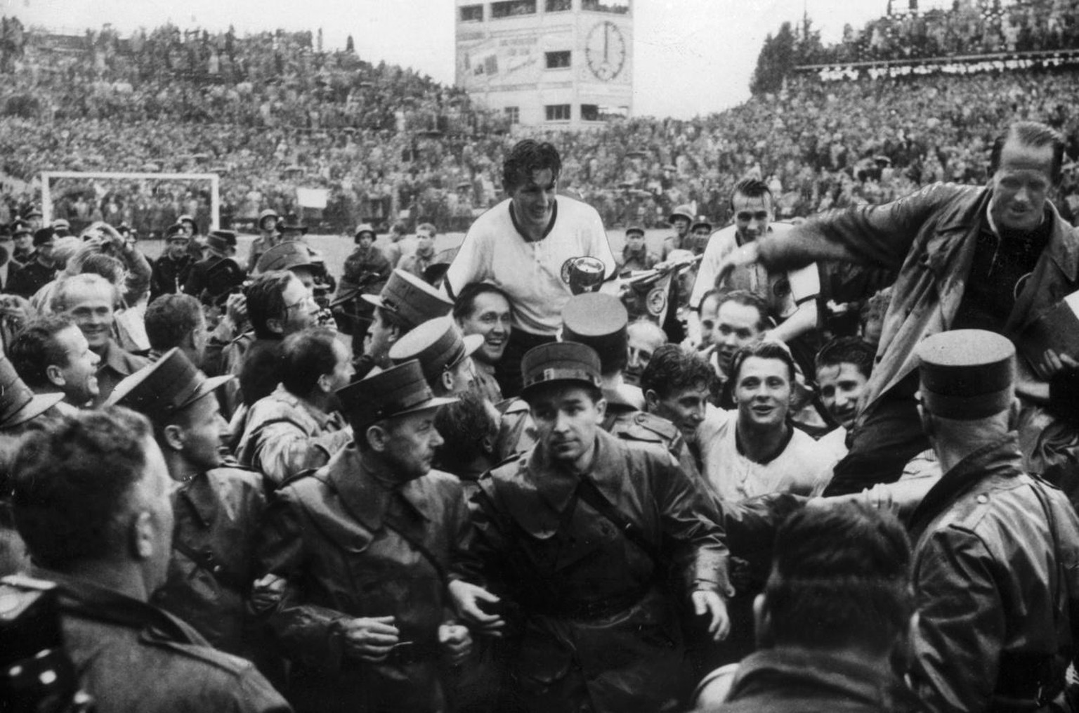 Nach dem WM-Finalspiel am 4. Juli 1954 in Bern werden der deutsche Captain Fritz Walter, Mitte, und Trainer Sepp Herberger, rechts, im Triumph auf den Schultern von begeisterten Anhaengern vom Spielfe ...