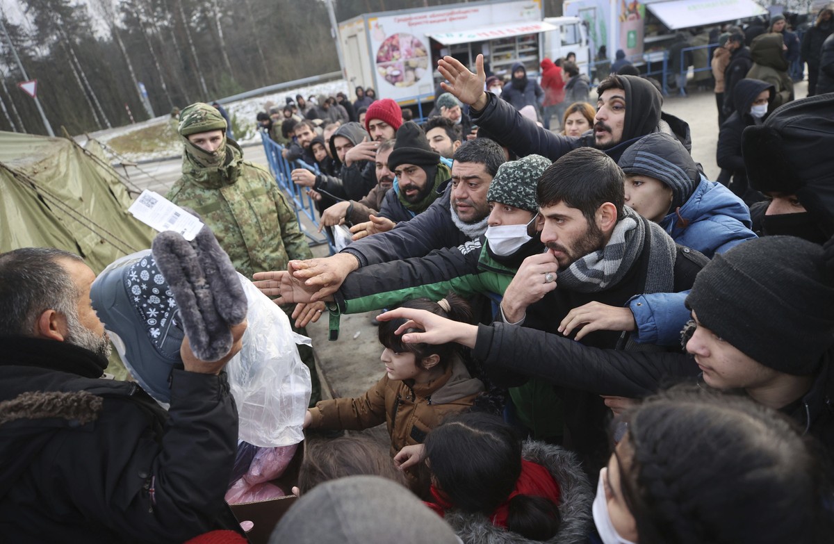 Migrants gather to get warm clothes inside a logistics center at the checkpoint "Kuznitsa" at the Belarus-Poland border near Grodno, in Grodno, Belarus, Sunday, Nov. 28, 2021. The West has a ...