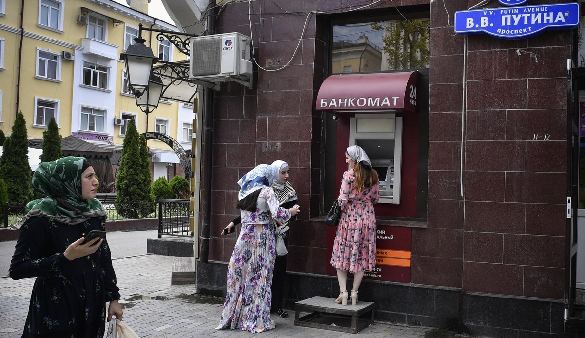 Ici, des femmes tchétchènes attendent devant un distributeur automatique de billets dans le centre-ville de Grozny, sur l'avenue Vladimir Poutine, le 26 juillet 2019.