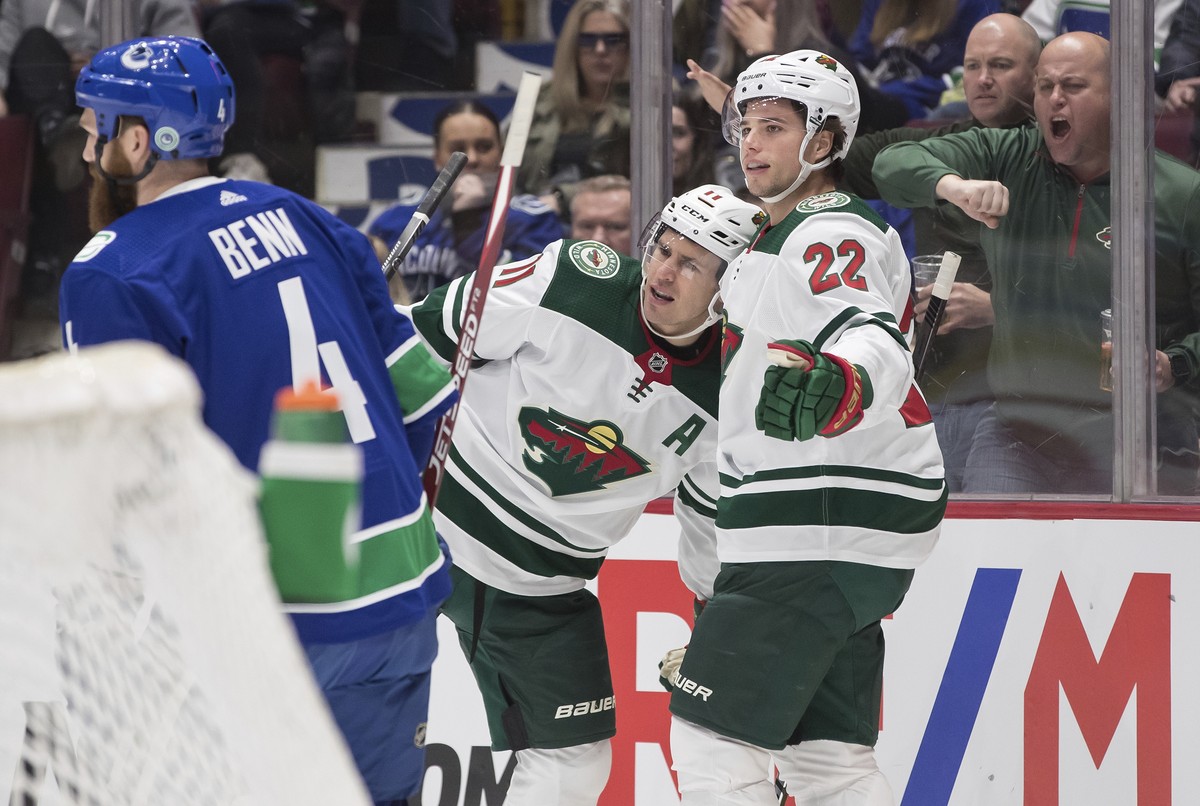 Minnesota Wild's Kevin Fiala, right, of Switzerland, and Zach Parise celebrate Fiala's goal as Vancouver Canucks' Jordie Benn skates past during the first period of an NHL hockey game W ...