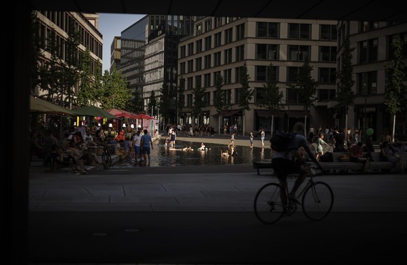 People take a bath in a water basin at Europaallee, central Zurich, as a heat wave reaches the country, in Zurich, Switzerland on Saturday, June 18, 2022. (KEYSTONE/Michael Buholzer)