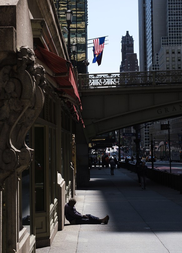 epa08364892 A man sits on the sidewalk in front of closed stores on 42nd street at Grand Central Terminal in New York, New York, USA, 15 April 2020. The United States? Commerce Department reported tha ...