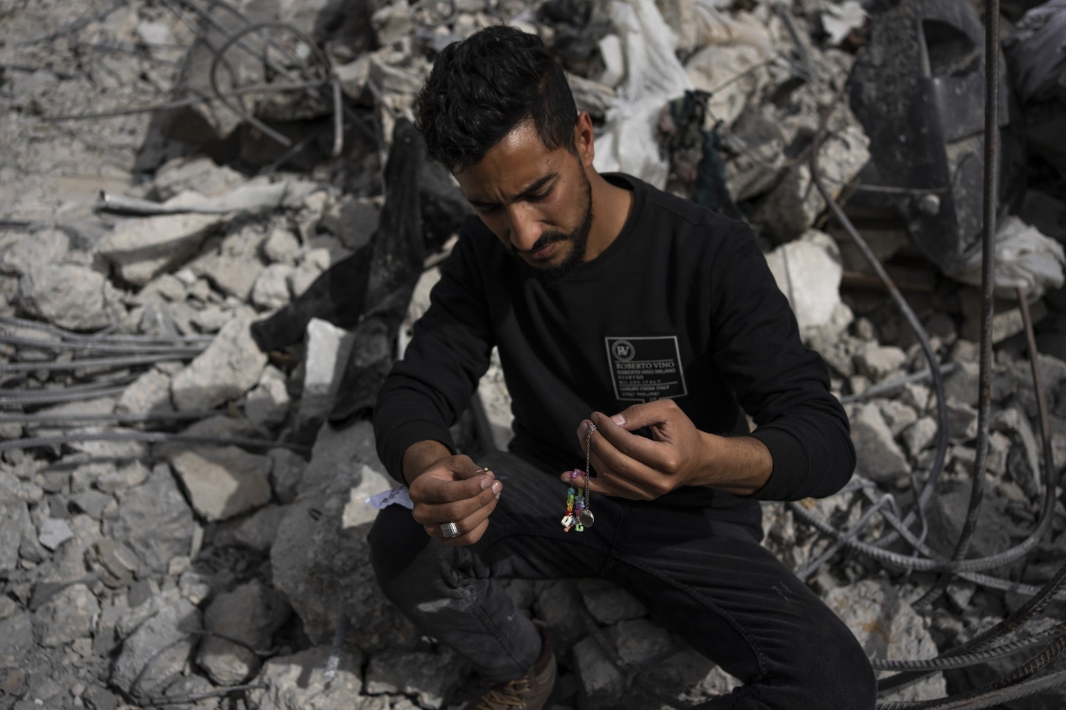 Ibrahim Hasouna, center, the sole survivor among his family, sits amidst the debris of his bombed home in Rafah, southern Gaza Strip, Tuesday, Feb. 13, 2024. On Monday, February 12, Hasouna lost eight ...