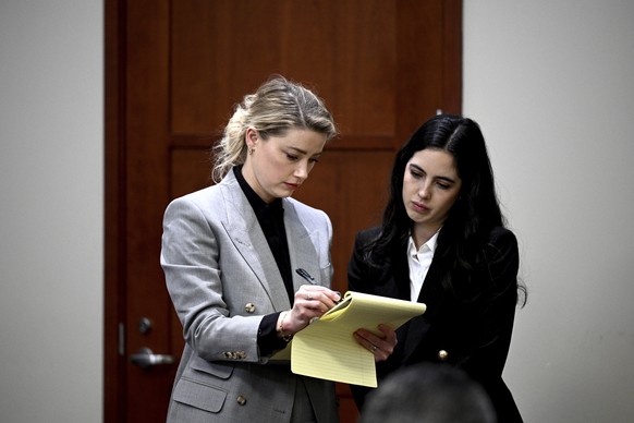 Actor Amber Heard, left, goes over documents in the courtroom at the Fairfax County Circuit Court, Tuesday, April 12, 2022, in Fairfax, Va. A jury in Virginia is scheduled to hear opening statements i ...
