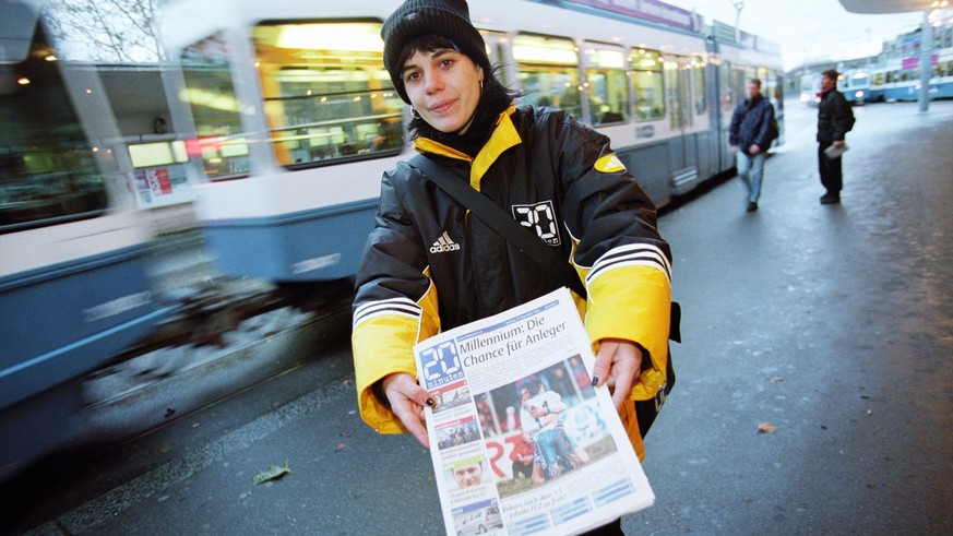 Eine Verteilerin der Gratiszeitung "20 Minuten" bietet am Tag der Lancierung des Gratisblatts beim Bellevue in Zuerich die Zeitung Passanten an, aufgenommen am 13. Dezember 1999. (KEYSTONE/C ...