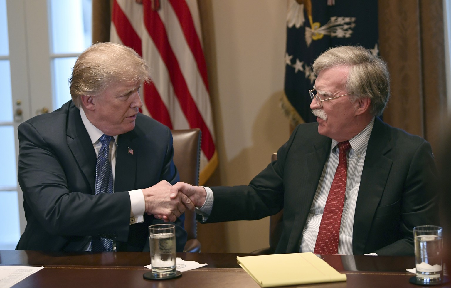 President Donald Trump, left, shakes hands with national security adviser John Bolton in the Cabinet Room of the White House in Washington, Monday, April 9, 2018, at the start of a meeting with milita ...