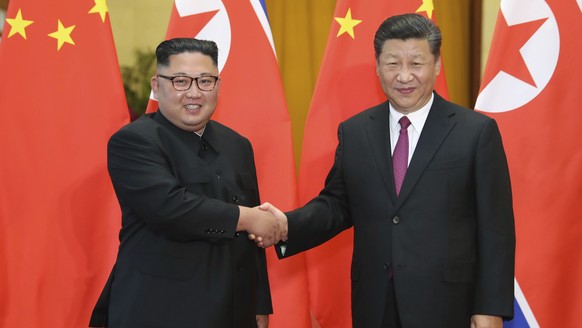 FILE- In this June 19, 2018, file photo provided by China&#039;s Xinhua News Agency, Chinese President Xi Jinping, right, shakes hands with North Korean leader Kim Jong Un, during a welcome ceremony a ...