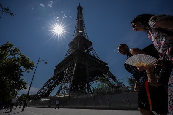People walk with a fan near the Eiffel Tower in Paris during a heat wave, Saturday, July 11, 2026. (AP Photo/Aurelien Morissard)
France Extreme Weather Heat