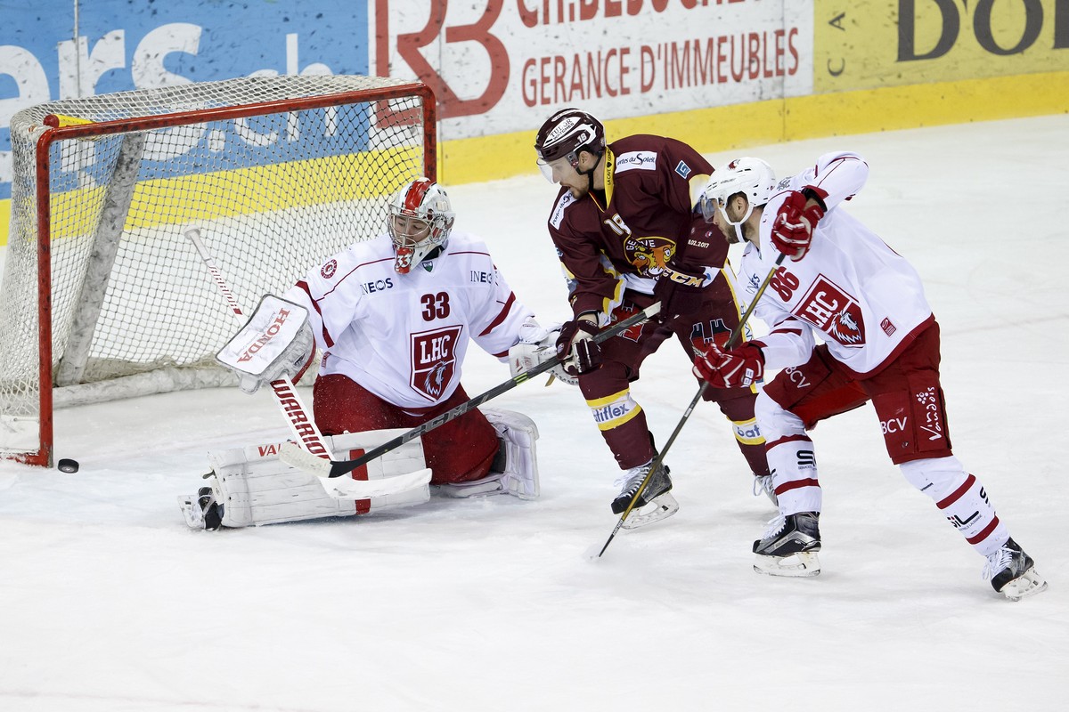 Lausanne's goaltender Pascal Caminada, left, saves a puck past Geneve-Servette's forward Jeremy Wick, center, and Lausanne's defender Dario Trutmann, right, during the game of National  ...