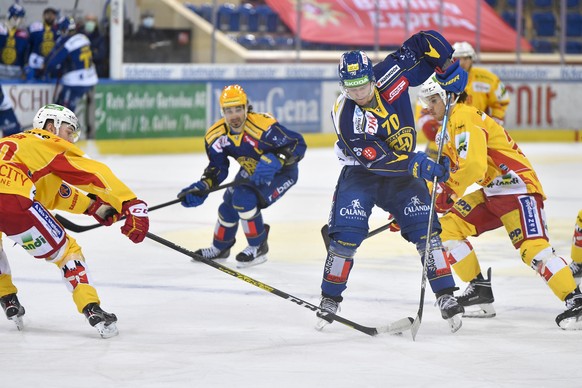 Der Davoser Enzo Corvi an der Scheibe gegen die Bieler Janis Jerome Moser, links und Yanni Rathgeb, rechts, im Eishockey-Qualifikationsspiel der National League zwischen dem HC Davos und dem EHC Biel, ...