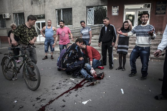 Bürger von&nbsp;Krasnoarmejsk helfen einem Verwundeten, der von ukrainischen Milizen angeschossen wurde.