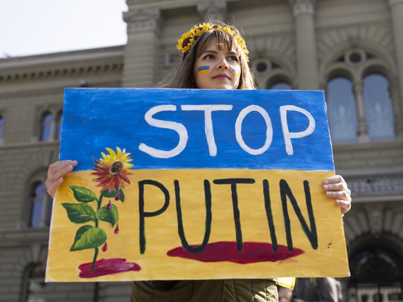 A Protester holds a &quot;Stop Putin&quot; banner on the Bundesplatz square during a demonstration against the Russian invasion of Ukraine in front of the Swiss parliament building in Bern, Switzerlan ...