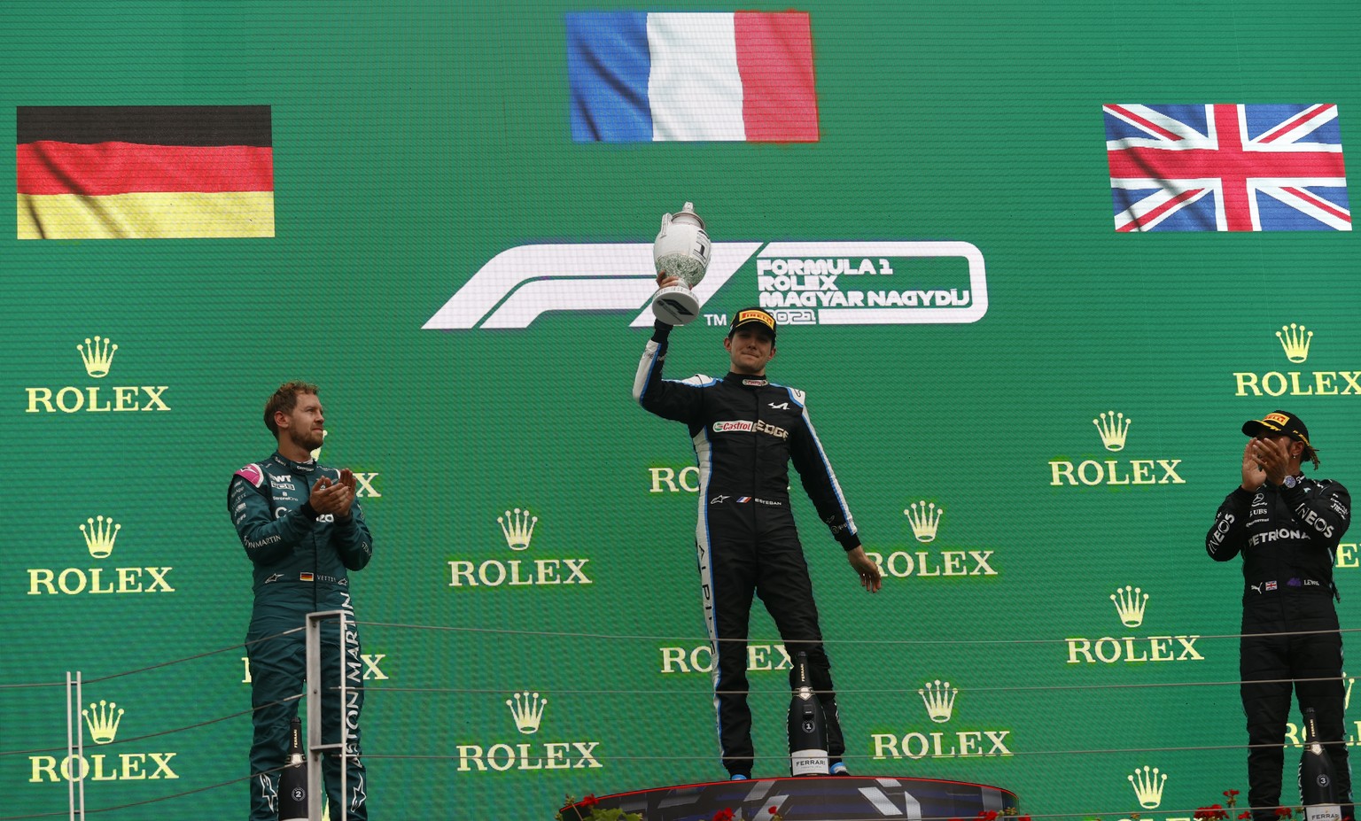 Race winner, Alpine driver Esteban Ocon of France, center, celebrates on the podium with second placed Aston Martin driver Sebastian Vettel of Germany, left, and third placed Mercedes driver Lewis Ham ...