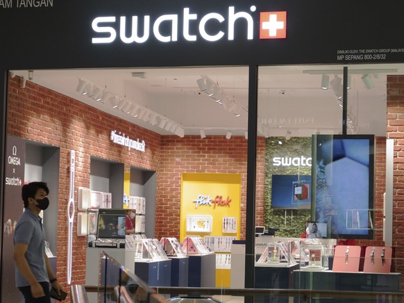FILE - A man walk pass Swatch outlet at a shopping mall in Putrajaya, Malaysia, Thursday, Aug. 10, 2023. (AP Photo/Vincent Thian, File)
